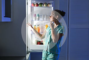 Woman choosing food from refrigerator in kitchen photo