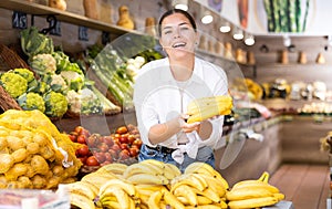 Woman choosing fresh bananas in fruit and vegetable section of supermarket