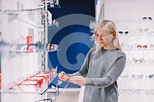 Woman choosing glasses at optics.