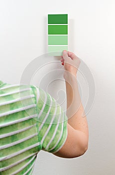 Woman choosing among green paint swatches