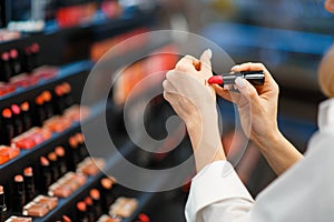 Woman choosing lipstick in cosmetics store