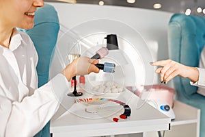 Woman choosing nail varnish in beauty salon