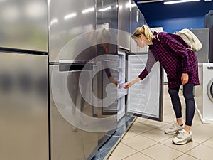 woman choosing new refrigerator in household appliances store