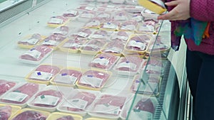 Woman choosing packed beef meat in supermarket