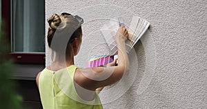 Woman choosing paint color for house exterior stucco facade