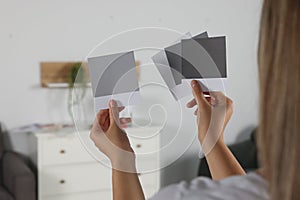 Woman choosing paint shade for wall in room, focus on hands with color sample cards. Interior design