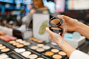 Woman choosing powder in cosmetics store