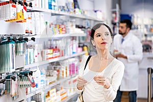 Woman choosing products with list at drugstore