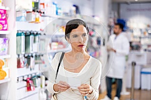 Woman choosing products with list at drugstore