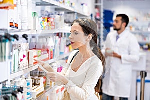 Woman choosing products with list at drugstore