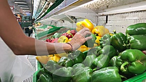 Woman choosing raw farm organic paprika in the supermarket.