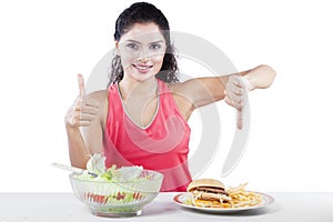 Woman Choosing Between Salad And Junk Food