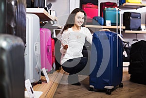 Woman choosing suitcase in shop