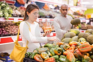 Woman choosing sweet pepper and man near choosing melon