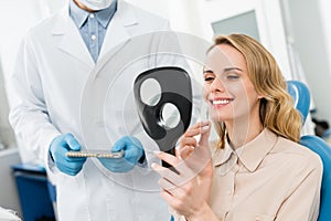 Woman choosing tooth implant looking at mirror in modern