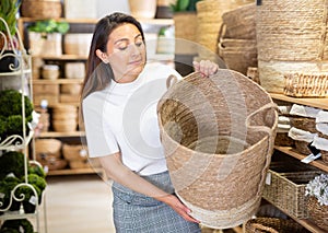 Woman choosing wicker basket in household goods store