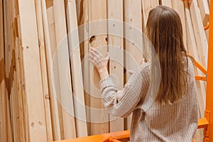 Woman choosing wooden plank in hardware store. Building materials for home renovation