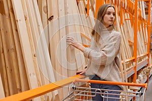 Woman choosing wooden plank in hardware store. Building materials for home renovation