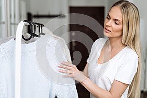 Woman choosing wool knitted sweater in pastel colours photo