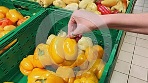 Woman choosing yellow sweet pepper in store.