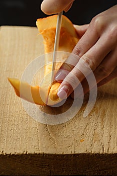 Woman chopping pumpkin on kitchen board, only hands visible. Autumn seasonal vegetables cooking. Healthy eating habits