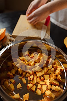 Woman chopping pumpkin on kitchen board, only hands visible. Autumn seasonal vegetables cooking. Healthy eating habits