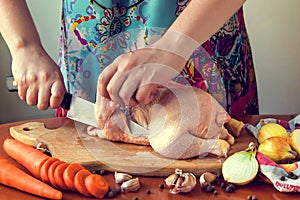 Woman chopping raw chicken for cooking