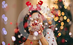 Woman, Christmas and blowing confetti for holiday celebration in home, sparkle or glitter. Female person, bokeh and