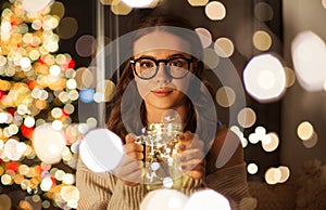 Woman with christmas garland lights in glass mug