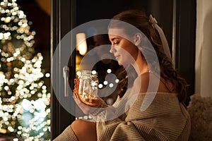 Woman with christmas garland lights in glass mug