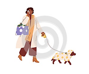 Woman with Christmas shopping bags, speaking on mobile phone, walking with dog. Happy girl with winter holiday purchases