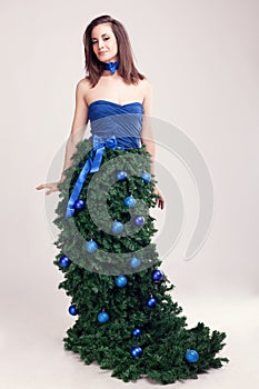 Woman in christmas tree dress on grey background