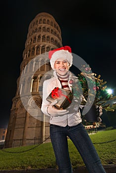 Woman with Christmas tree and gift box near Leaning Tower, Pisa