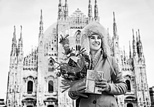 Woman with Christmas tree and gift looking into distance, Milan