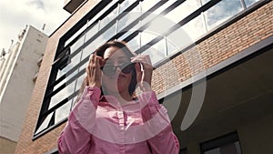 woman circles around herself against the business buildingand puts on sunglasses