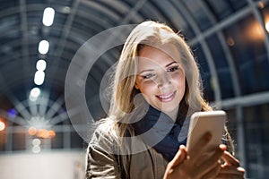 Woman in the city at night holding smartphone, texting. photo