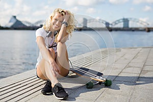Woman in city sitting on pavement with longboard photo