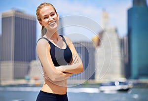 Woman, city and smile at river side in sportswear to jog, fitness and healthy mindset in New York. Portrait, female