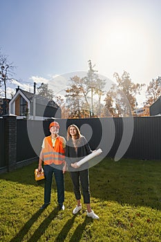 Woman civil engineer and worker standing on house lawn