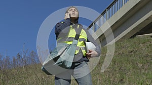 Woman civil inspector talking on phone near bridge