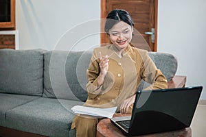 woman in civilian uniform use laptop and paperwork while sitting with hand gestures to explain