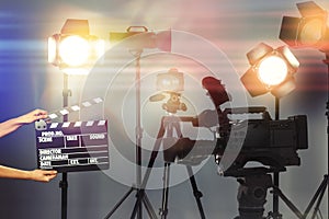 Woman with clapperboard near modern professional video camera in studio