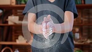 Woman clapping hands with wheat flour on palms in home kitchen, flour flying around, slow-motion