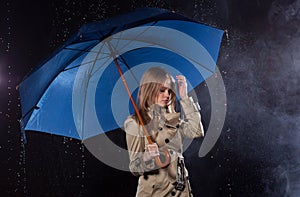 Woman in classic trench coat with umbrella in rain