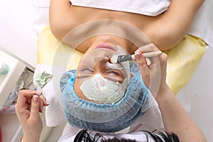 Woman with clay facial mask in beauty spa.