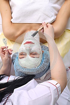 Woman with clay facial mask in beauty spa.