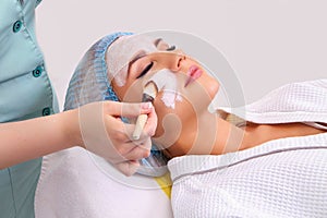 Woman with clay facial mask in beauty spa.