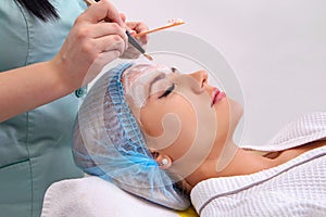 Woman with clay facial mask in beauty spa.