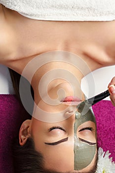 Woman with clay facial mask   in beauty spa. Skincare. Beauty Concept. Close-up portrait of beautiful girl applying facial mask.