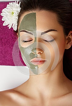 Woman with clay facial mask   in beauty spa. Skincare. Beauty Concept. Close-up portrait of beautiful girl with facial mask.Facial